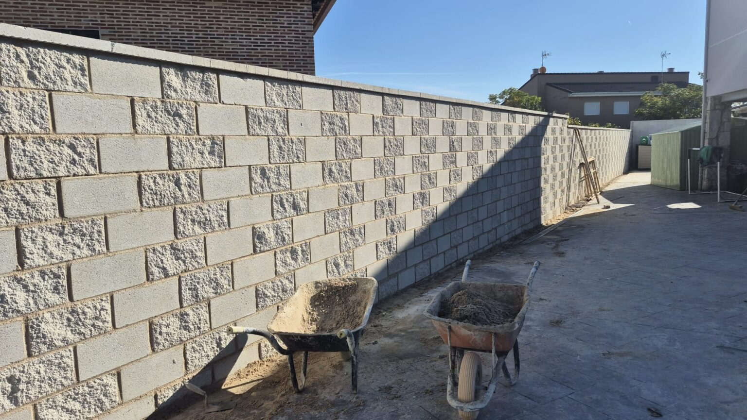 Operario levantando un muro de bloque de hormigón para un cerramiento perimetral.